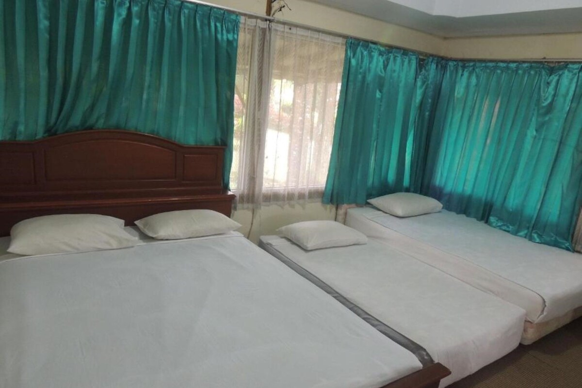 Une chambre avec trois lits simples, chacun étant équipé de draps et d’oreillers blancs.