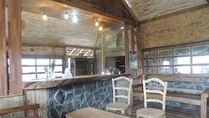 Un interior rústico de madera con paredes de piedra, una barra de madera y sencillas sillas de madera.
