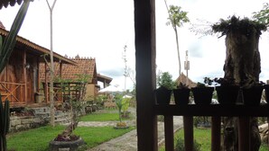 Una casa tradicional de madera con tejado de baldosas, rodeada de un jardín con plantas en macetas y un camino de piedra.