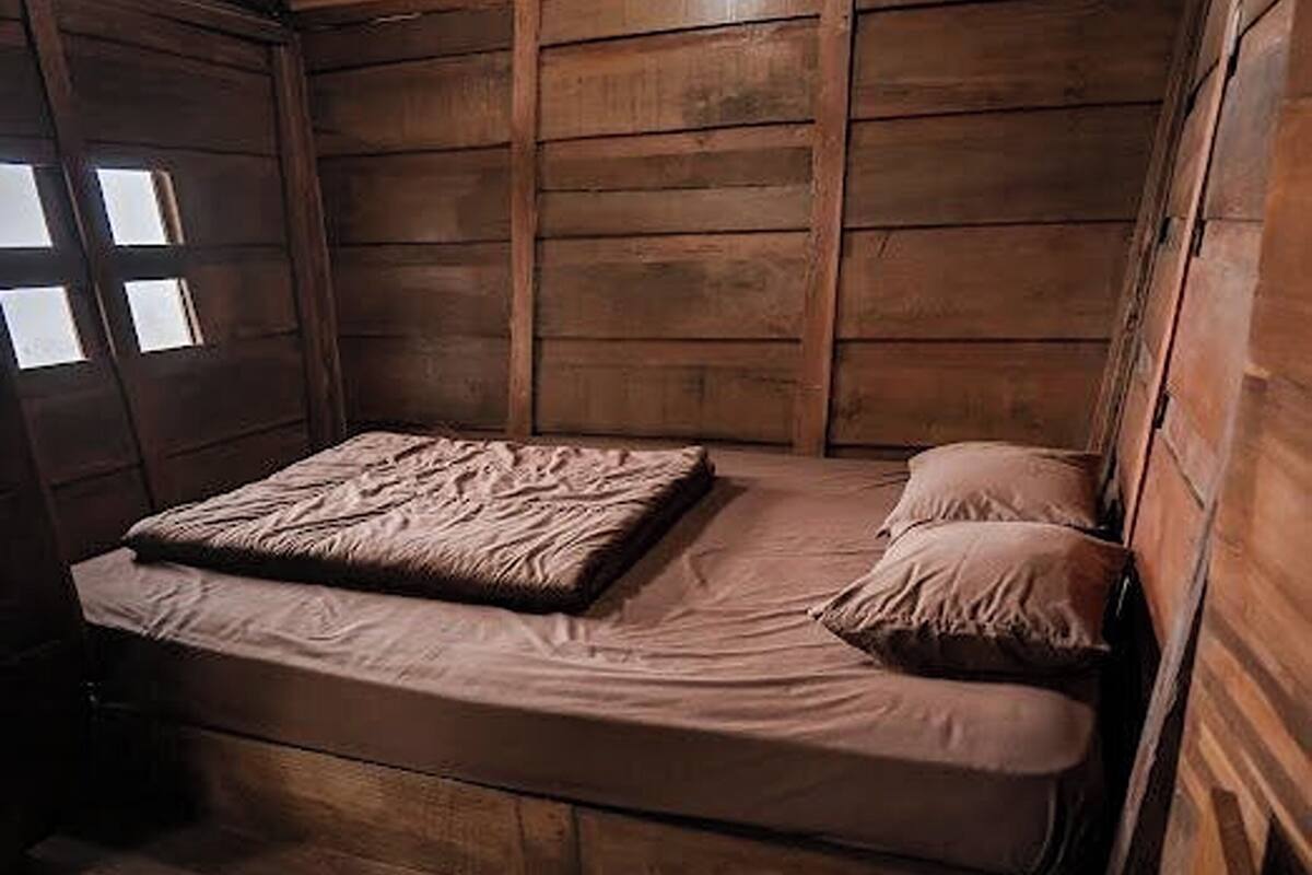 Um quarto pequeno estilo cabana, com uma cama e uma janela.