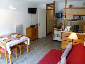 A compact living space with a dining area, kitchenette, and a red sofa. - 5-person Studio with pets and parking in Contamines (Les Contamines-Montjoie)
