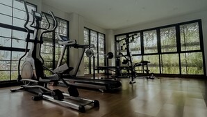 A gym with cardio machines and free weights, large windows, and a wooden floor. - Mendjangan Residence (Jakarta)