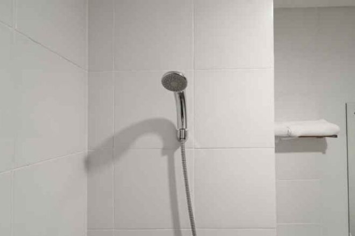 Chuveiro com chuveiro manual e porta-toalhas.