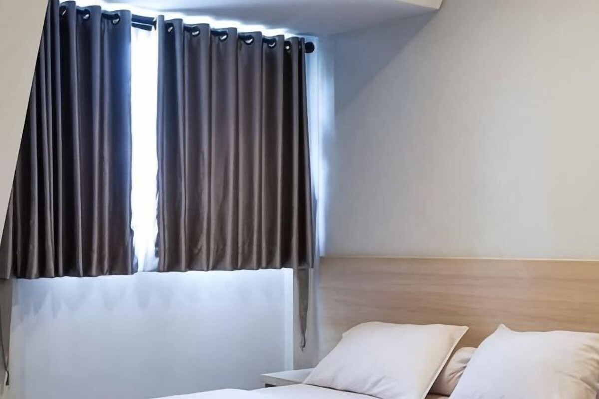 A hotel room with a bed, curtains, and a headboard.