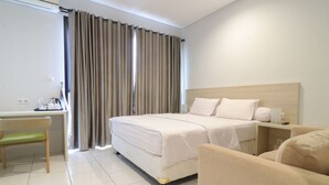 A hotel room with a bed, a desk, a chair, and a sofa. - Mendjangan Residence (Jakarta)