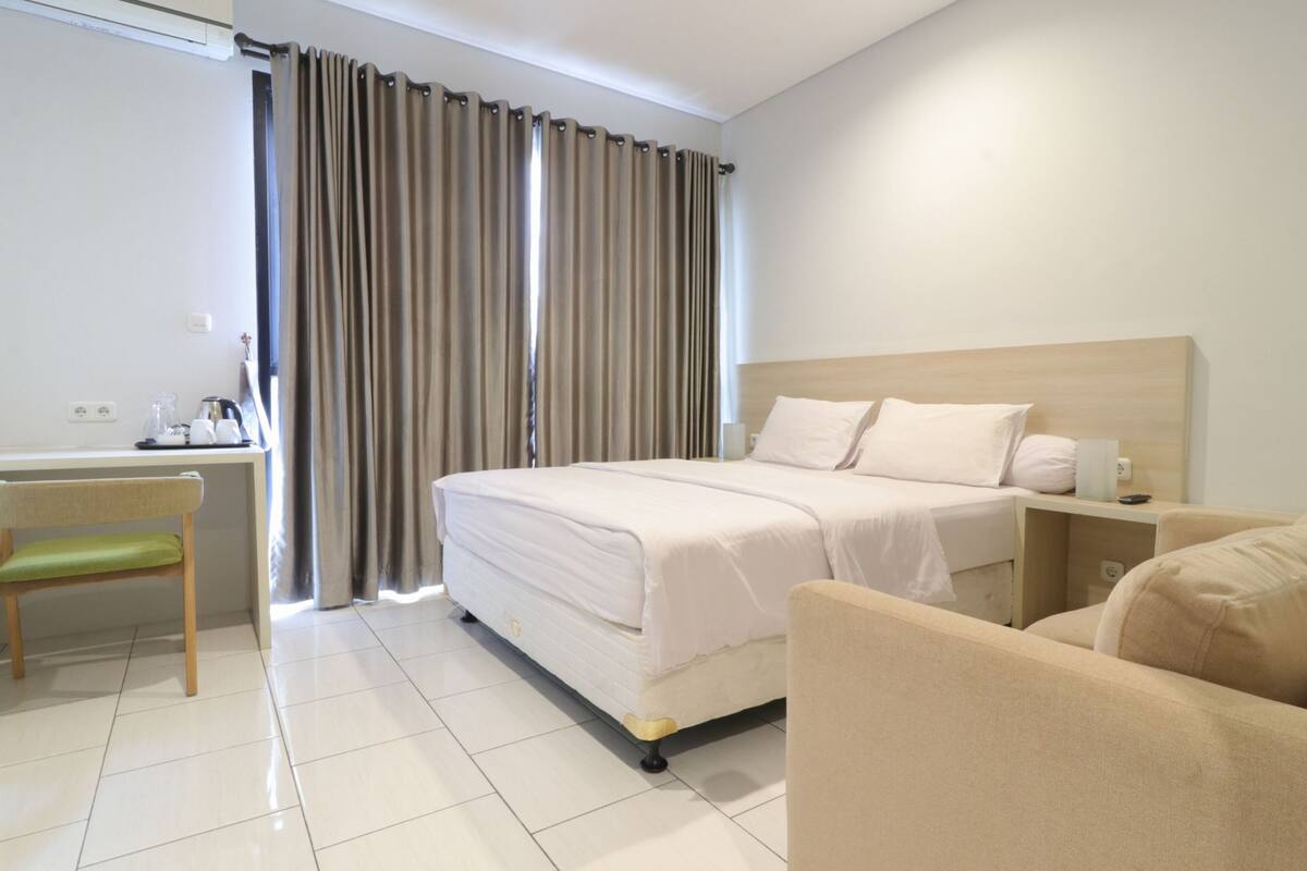 A hotel room with a bed, a desk, a chair, and a sofa.
