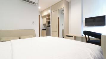 A hotel room with a bed, a desk, a chair, a TV, and a wardrobe.