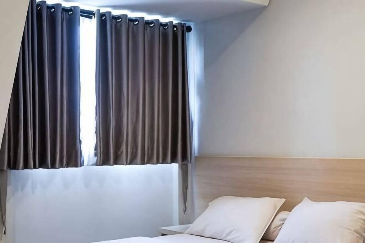 A hotel room with a bed, curtains, and a headboard.
