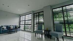 A spacious room with large windows, a sofa, two armchairs, and a small table. - Mendjangan Residence (Jakarta)