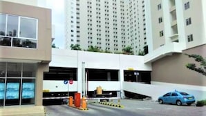 A multi-story parking garage with a modern design, featuring a ramp leading to a lower level. - Apartement Educity Tower Y-P-H By Prafi (Surabaya)