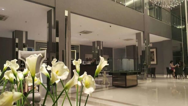 A modern lobby with a glass railing, a chandelier, and a reception desk. - Apartement Educity Tower Y-P-H By Prafi (Surabaya)