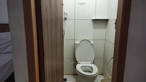 A small, basic bathroom with a toilet, a sink, and a shower. - De' Premium Hotel Musi Raya (Palembang)
