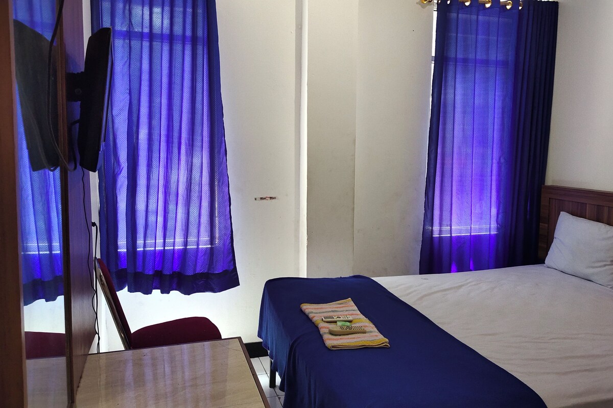 A room with a single bed, a wooden headboard, and a desk with a chair.