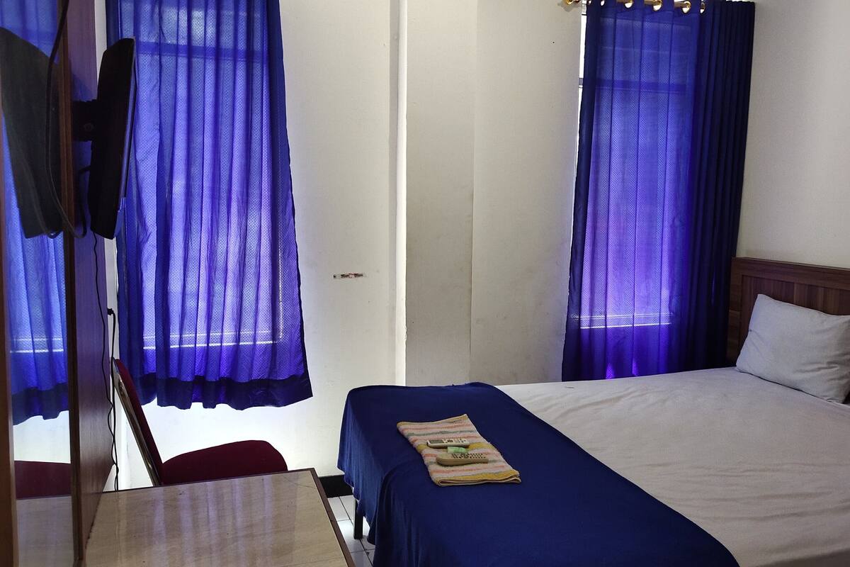 Une chambre avec un lit simple, une tête de lit en bois et un bureau avec une chaise.