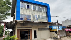 A two-story building with a blue facade, a visible entrance, and signage for 'PARFUM' and 'De' PREMIUM Hotel. - De' Premium Hotel Musi Raya (Palembang)