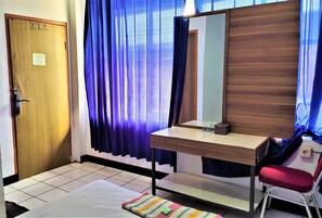 Une pièce avec une porte en bois, un bureau doté d’un miroir, une chaise rouge et un tapis à rayures.