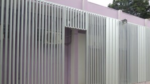 En bygning med lilla facade og en metalport.