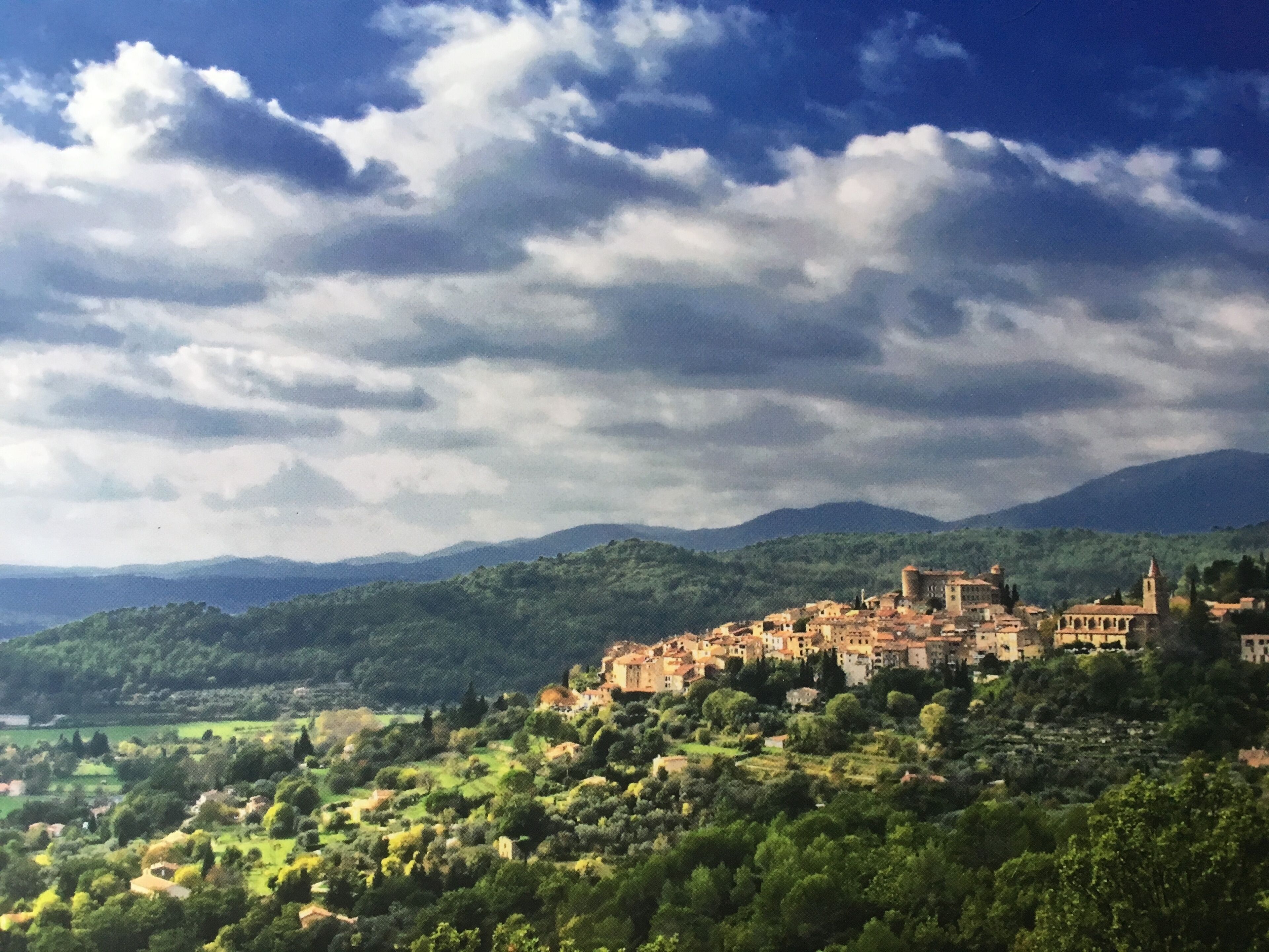 Une ville chargée d’histoire, dotée d’une architecture médiévale, entourée de collines verdoyantes et surplombée d’un ciel nuageux.