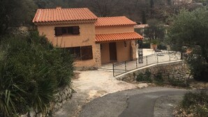 Una casa a due piani con tetto in tegole, un muro in pietra e un cancello in metallo.