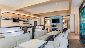 A modern hotel lobby with a bar area, seating arrangements, and a television screen. - Hyatt House Davis (Davis)