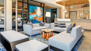 A modern hotel lobby with a seating area, a large abstract painting, and a reception desk. - Hyatt House Davis (Davis)