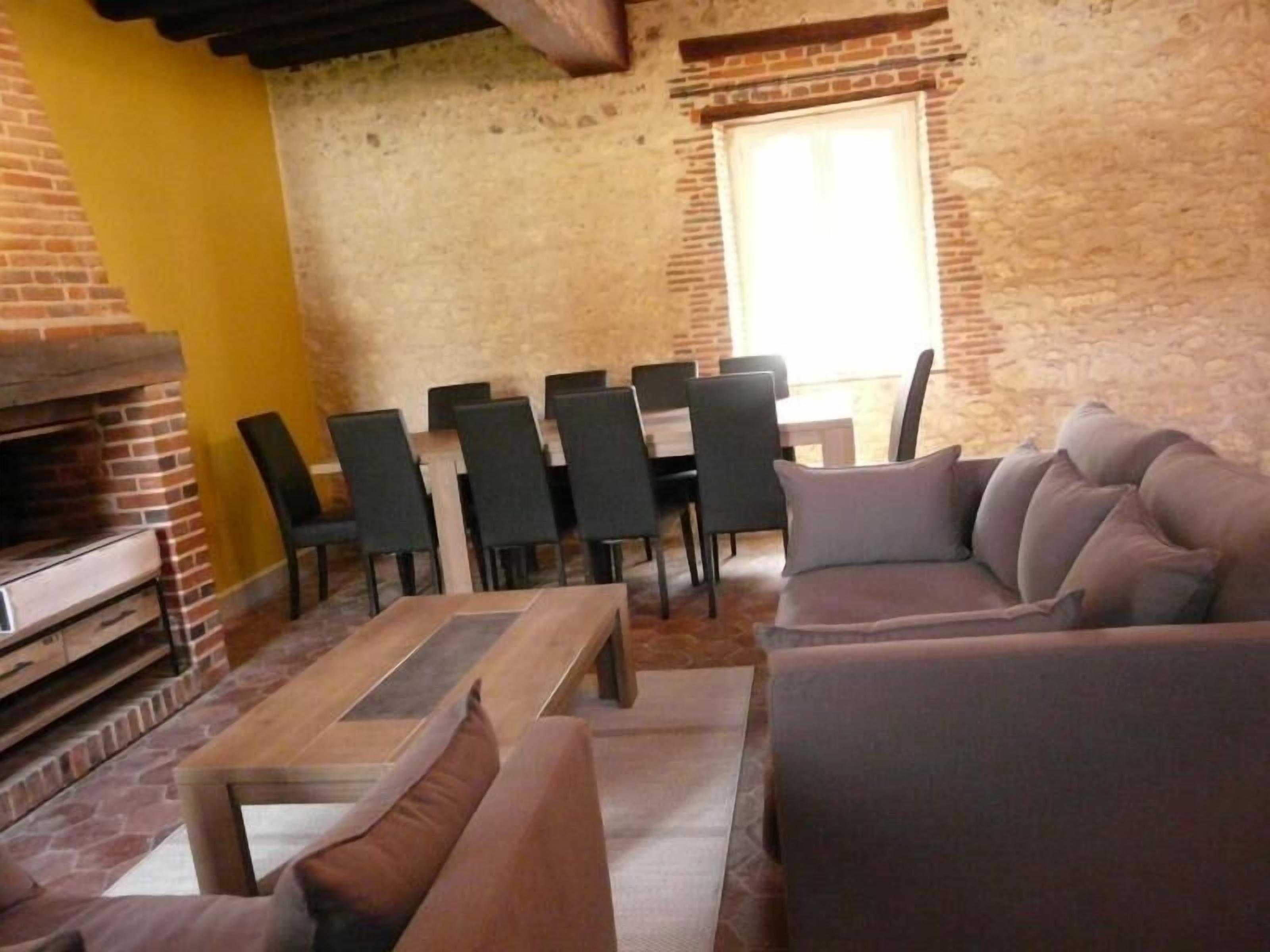 Un salon chaleureux avec une cheminée en briques, un canapé, une table basse et une table à manger avec des chaises.