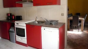 Una cocina compacta con armarios rojos, una estufa blanca y un lavavajillas.