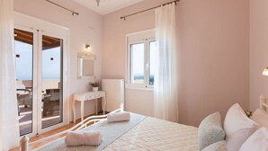 Ein Schlafzimmer mit einem Bett, einem Nachttisch, einem Spiegel, einem Fenster und Blick ins Freie.