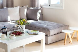 Un salon moderne avec un canapé, une table basse, un vase de fleurs, un panier de fraises et un magazine.