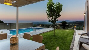 Ein Poolbereich mit Tisch und Stühlen, einem Baum und Blick auf die Landschaft.
