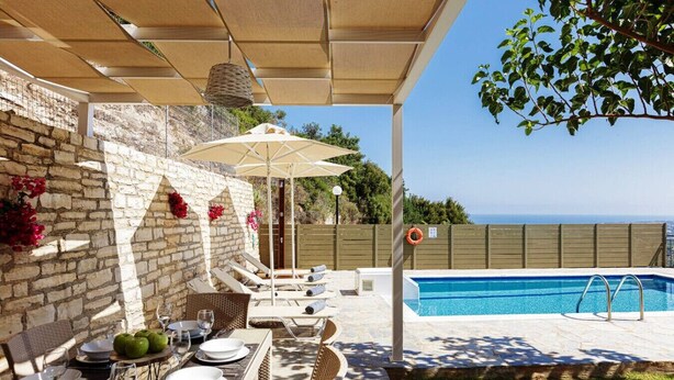 Ein Poolbereich mit Esstisch, Pool und Blick auf das Meer.