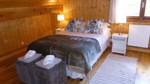 Ein Schlafzimmer mit Holzwänden, einem Bett, zwei Nachttischen mit Lampen, einem Heizkörper und einem Teppich.