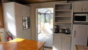 Eine Küche mit weißen Schränken, einer Holzarbeitsplatte, einem eingebauten Backofen, einer Kaffeemaschine und einer Mikrowelle.