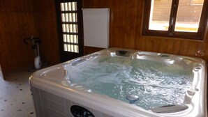 Eine Whirlwanne mit Bedienfeld, ein Fenster mit Jalousien und ein Heizkörper.