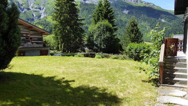 Eine Blockhütte mit einem Rasen und einer Steintreppe, die zu einer Holzterrasse führt.