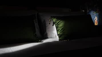 Um quarto com pouca luz, com uma cama adornada por almofadas verdes e brancas.