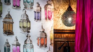A wall with variously designed lanterns and a single hanging lantern.