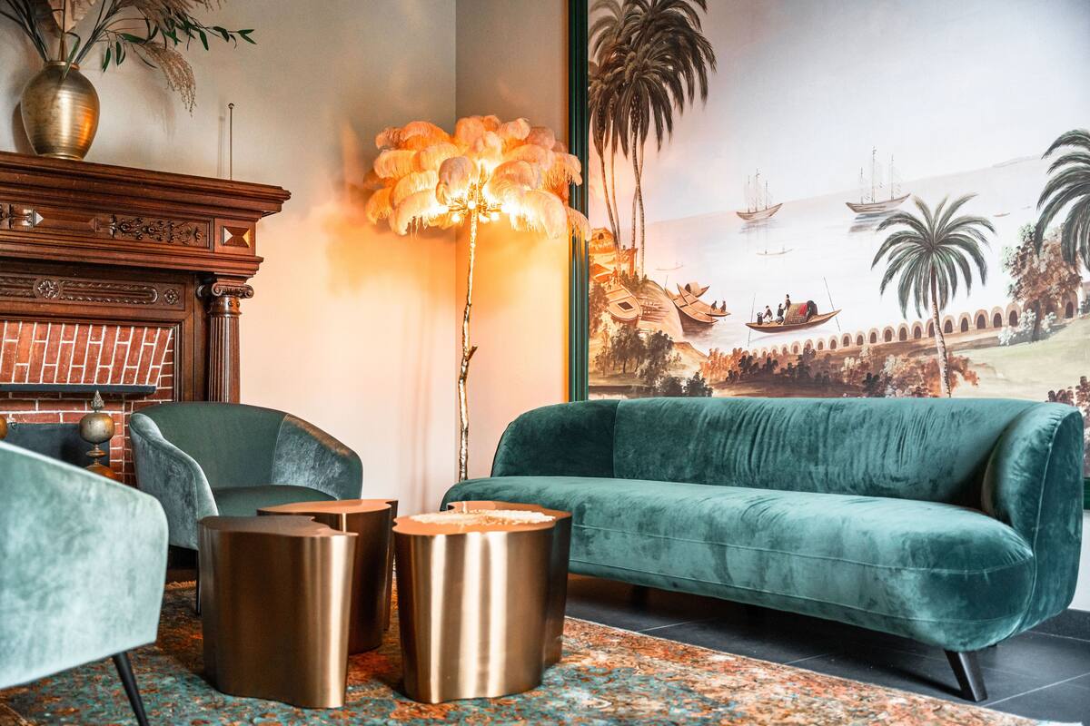 A living room with a green sofa, two metallic side tables, a floor lamp, and a fireplace.