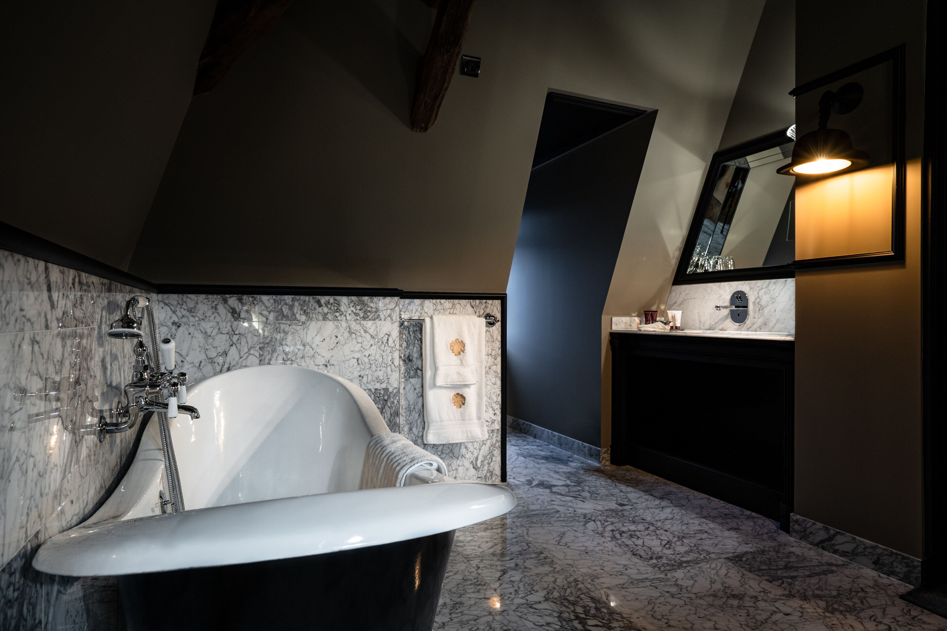 A bathroom with a freestanding bathtub, a marble-tiled shower area, and a dark-toned vanity.