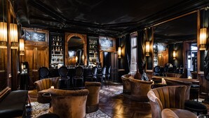 A bar area with wooden furniture, a bar counter, and a mirrored wall. - Le Chateau de Maubreuil (Carquefou)