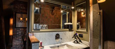 A modern bathroom with a large mirror, a marble sink, and a brick wall.