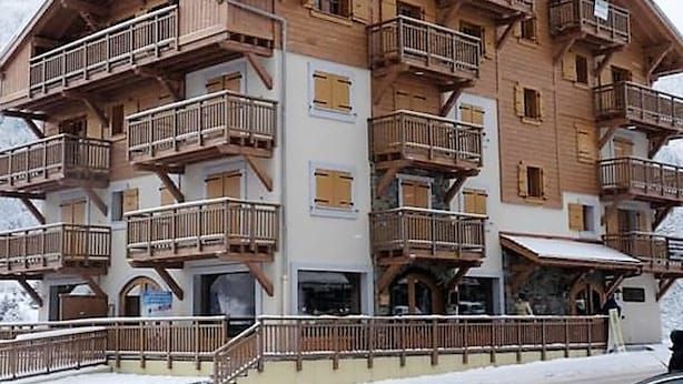Un edificio de madera de varios pisos con balcones, probablemente un hotel o una posada.