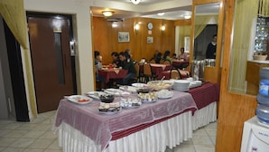 A dining area with tables covered in tablecloths, serving trays with food, and a water dispenser. - Hotel Oz Villa (Istanbul)