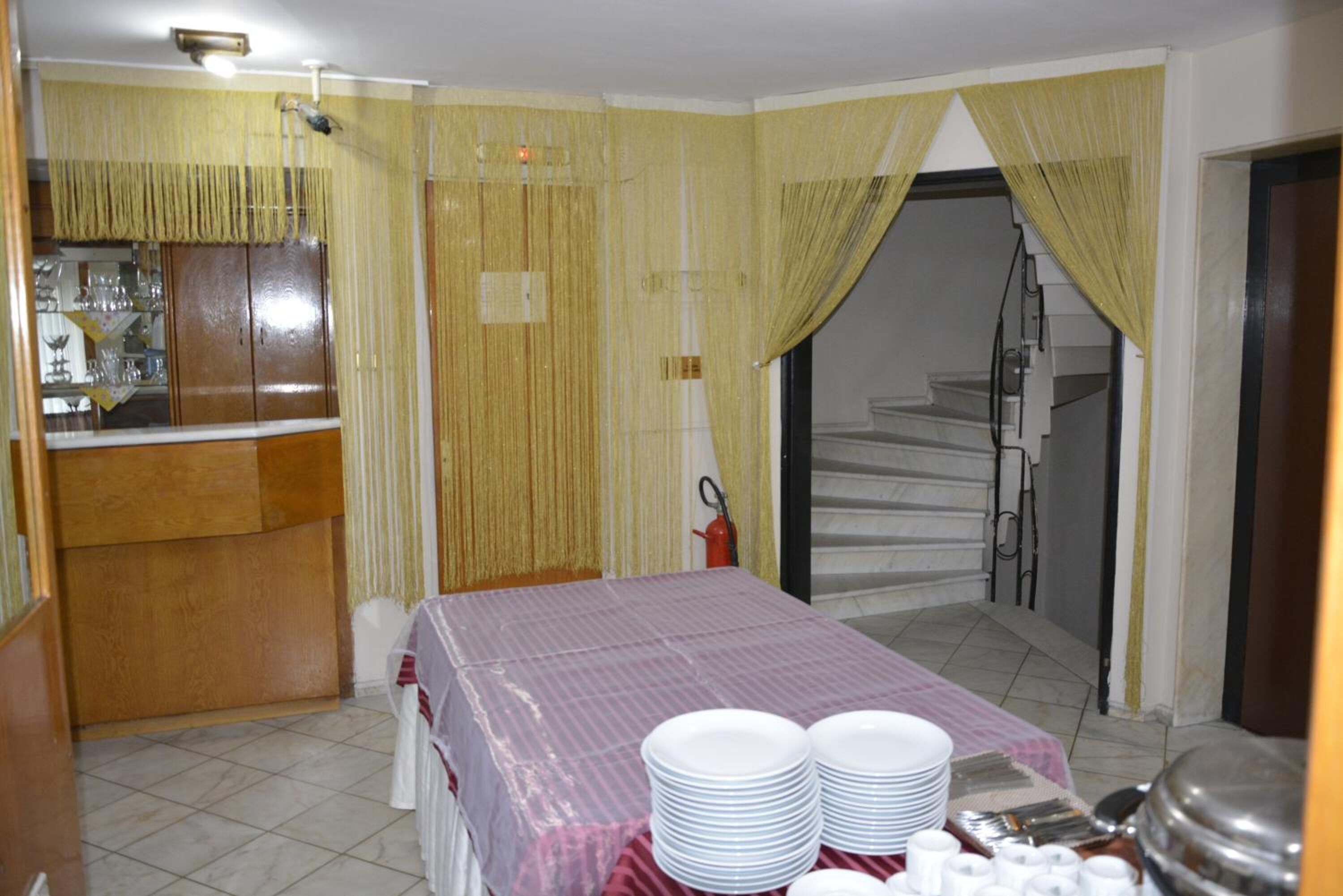 A hotel room with a bed, a dining table with plates and cutlery, a minibar, and a staircase leading to an upper floor.