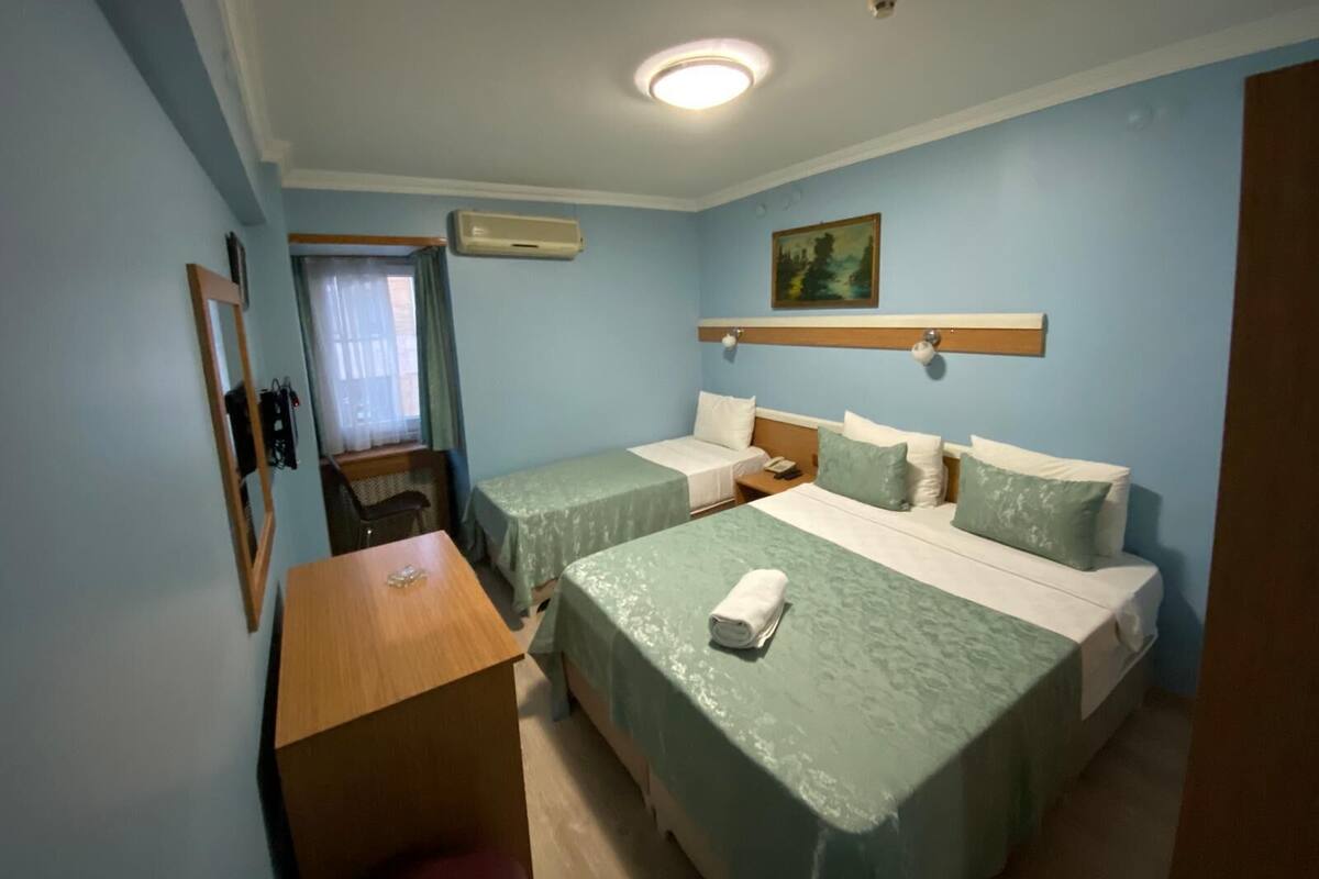 A hotel room with two beds, a desk, a chair, and a painting on the wall.