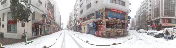 A street view with a snow-covered road, buildings with various signs, including a visible 'HOTEL VILLA' sign, and parked cars. - Hotel Oz Villa (Istanbul)