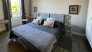 A bedroom with a bed, bedside tables, a desk, and a window with curtains.