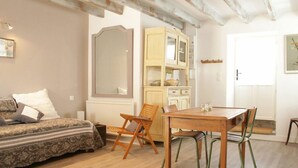 A cozy room with a sofa, a dining table with chairs, a cabinet, and a large mirror.