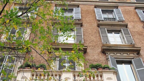Ein mehrgeschossiges Gebäude im klassischen Stil, mit einem markanten Bogenportal und zahlreichen Fenstern mit Fensterläden.