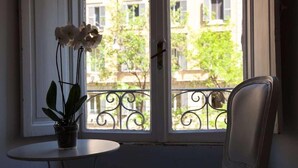 Ein Zimmer mit Fenster, einer Topfpflanze und einem Stuhl.